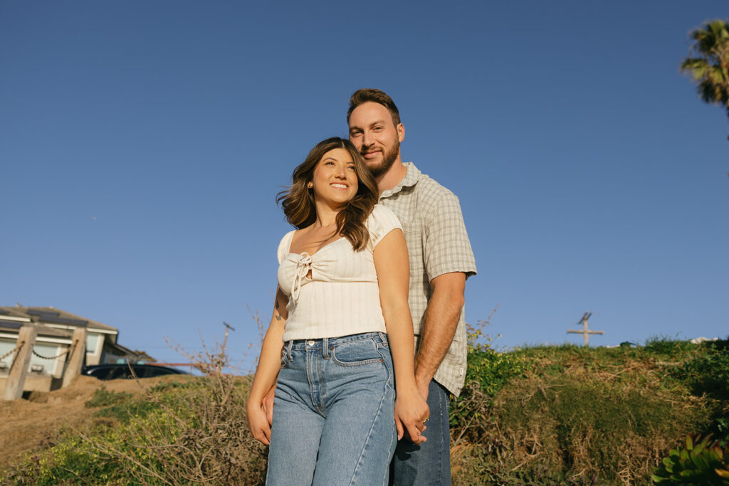 A Southern CA couple is photographed in golden light before a blue sky during their beachside California engagement photos with Allison Nicole Photo 