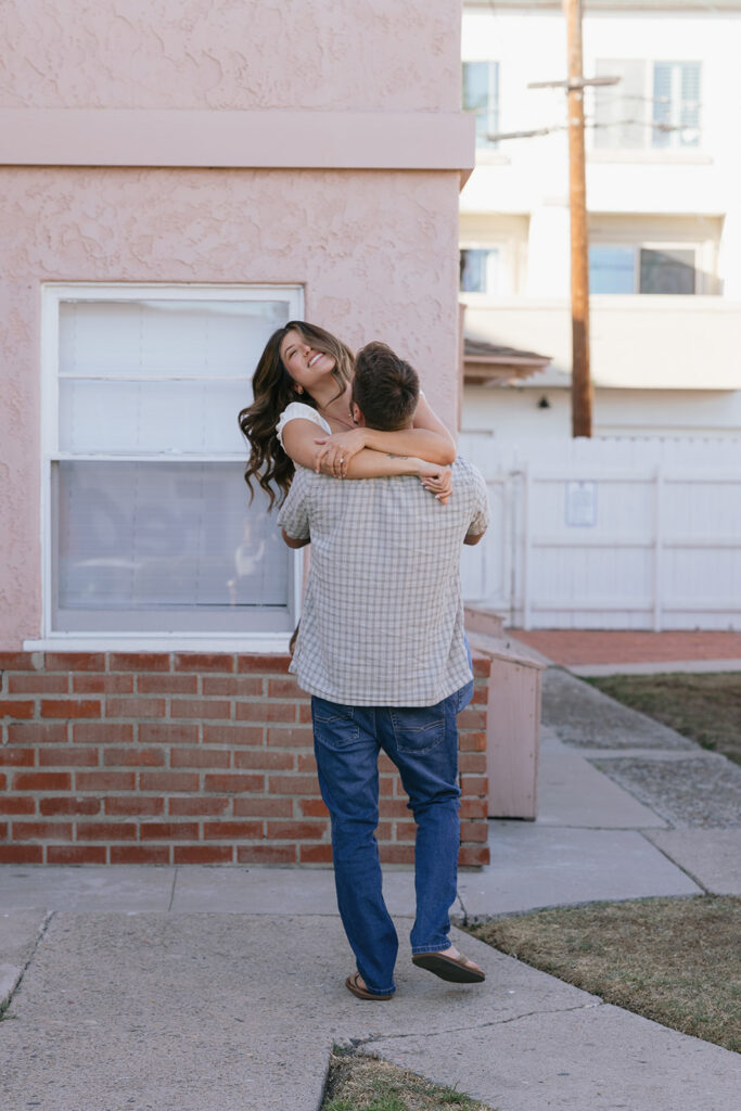 A man carries his brunette fiancée away from the camera, laughing, during their CA engagement photos 